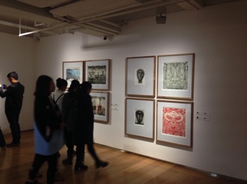Students lookng at prints by Ian Phillips, Jimmy Pasakos, Alfonso Fernandez and Judy Macklin
